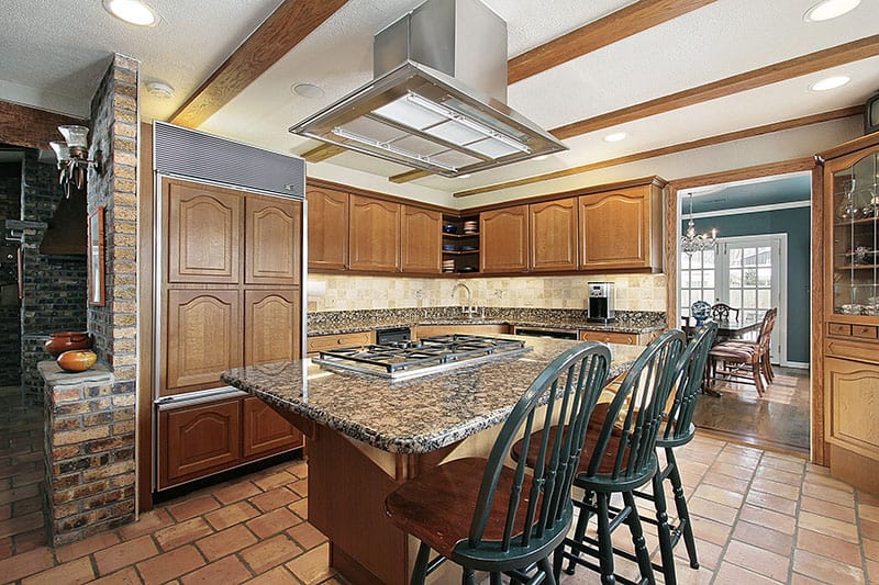 Deeply Veined Marble Countertop Island With Brick And Wood Cabinetry In A Rustic Kitchen